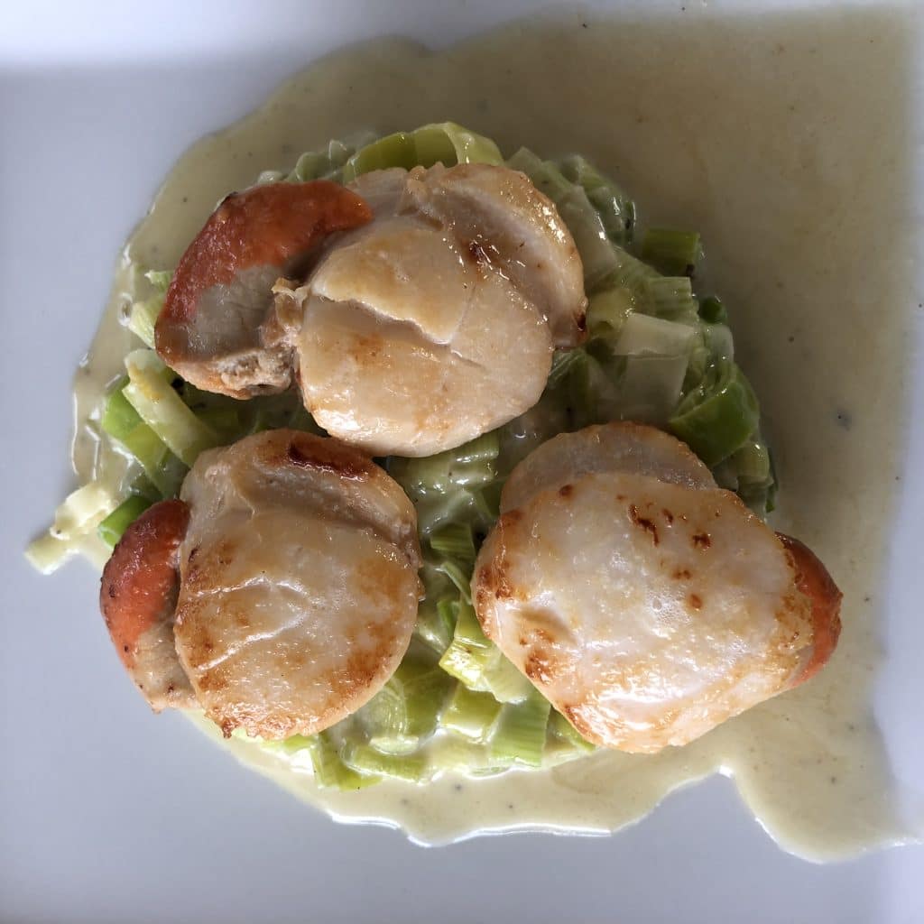 Three scallops on a bed of leeks